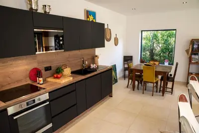 a kitchen with black cabinets and a dining room at Les Villas de Palombaggia in Porto-Vecchio