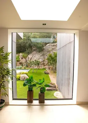 a room with a view of a garden through a window at Les Villas de Palombaggia in Porto-Vecchio