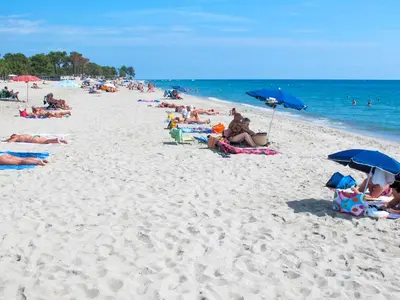 a group of people sitting on a beach with umbrellas at Apartment A Suara Linda-2 by Interhome in Ghisonaccia