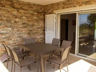a wooden table and chairs on a patio at Apartment A Suara Linda-1 by Interhome in Ghisonaccia