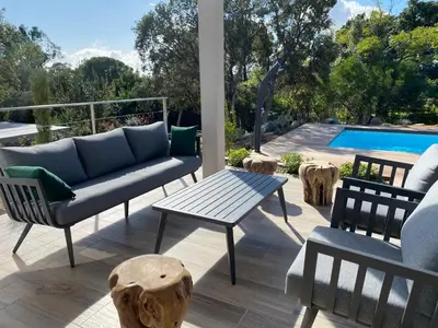 a patio with a couch and a table and a pool at VILLA ISULA by Intendance Excellency in Sainte-Lucie de Porto-Vecchio