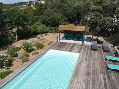 a swimming pool with chairs and a wooden deck at VILLA ISULA by Intendance Excellency in Sainte-Lucie de Porto-Vecchio