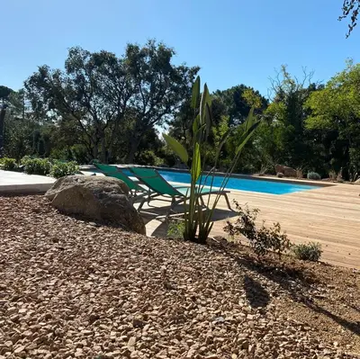 a pool with a bench and a plant and a rock at VILLA ISULA by Intendance Excellency in Sainte-Lucie de Porto-Vecchio