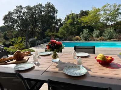 a wooden table with plates and flowers on it next to a pool at VILLA ISULA by Intendance Excellency in Sainte-Lucie de Porto-Vecchio