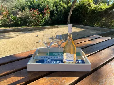a bottle of wine and two glasses on a table at VILLA ISULA by Intendance Excellency in Sainte-Lucie de Porto-Vecchio