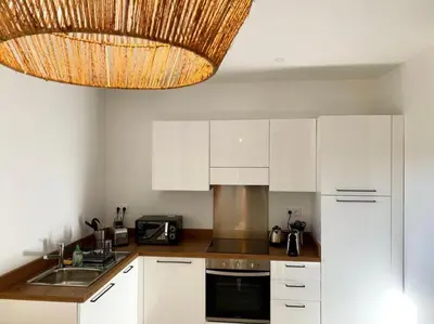 a kitchen with white cabinets and a chandelier at Résidence Casarella Lama in Lama