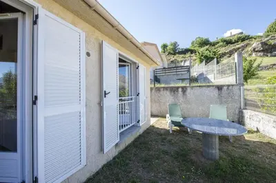 a patio with a table and chairs and a building at Terrasse de Malbeccu in Casamaccioli