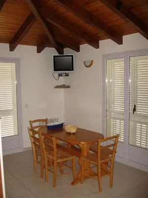 a dining room table with chairs and a tv on the wall at Terrasse de Malbeccu in Casamaccioli