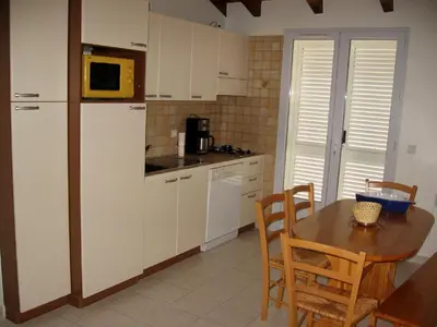 a kitchen with white cabinets and a table with chairs at Terrasse de Malbeccu in Casamaccioli
