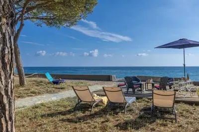 a group of chairs and an umbrella on the beach at Villa Les 3 frères in San-Nicolao