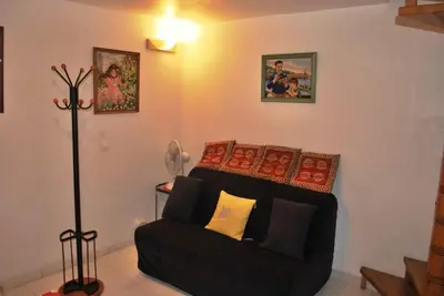 a living room with a black couch and pictures on the wall at L'Appart in Bonifacio