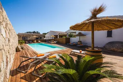 a pool with an umbrella and chairs and a swimming pool at Résidence Petra d'Oro - Villa Chiappa in Porto-Vecchio
