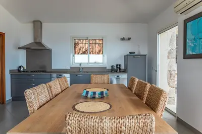 a kitchen with a wooden table and some chairs at Villa Bella Vista Di Pinarello in Sainte-Lucie de Porto-Vecchio