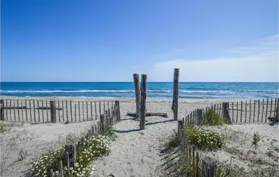 a sandy beach with a fence and the ocean at Amazing Home In Borgo With Kitchen in Borgo