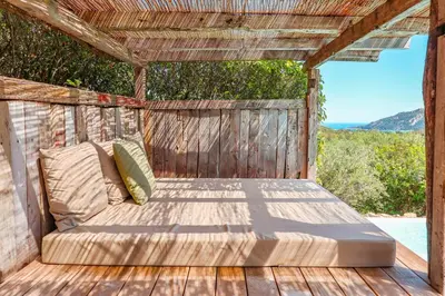 a bed on a wooden deck with a view of the ocean at Casa Sarralonga Di Porto-Vecchio in Porto-Vecchio