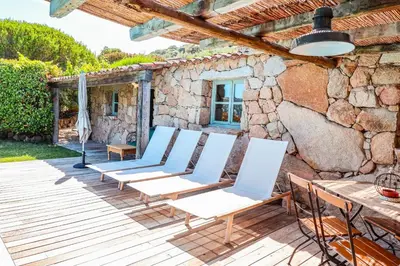 a group of chairs on a deck with a stone wall at Casa Sarralonga Di Porto-Vecchio in Porto-Vecchio