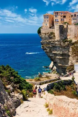 a group of people walking down a path next to the ocean at Maison de Plage à pied San Cipriano 5 pers in Lecci