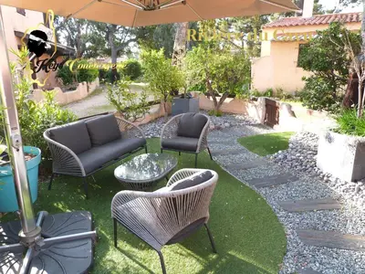 a patio with chairs and tables and an umbrella at Maison de Plage à pied San Cipriano 5 pers in Lecci