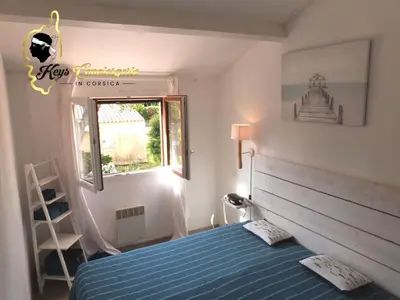 a bedroom with a blue bed and a window at Maison de Plage à pied San Cipriano 5 pers in Lecci