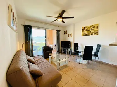 a living room with a couch and a table at A Funtana deux chambres, vue mer, piscine et tennis in Propriano