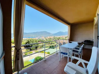 a balcony with a table and chairs and a large window at A Funtana deux chambres, vue mer, piscine et tennis in Propriano