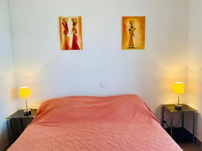 a bedroom with a bed and two lamps on two tables at A Funtana deux chambres, vue mer, piscine et tennis in Propriano
