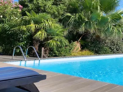 a swimming pool with a wooden deck and palm trees at VILLA TORRACCIA 4 Étoiles in Sainte-Lucie de Porto-Vecchio