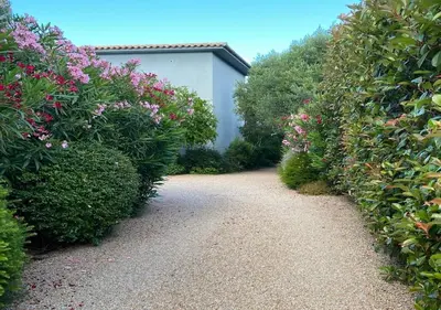 a garden path with bushes and a white building at VILLA TORRACCIA 4 Étoiles in Sainte-Lucie de Porto-Vecchio