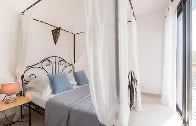 a white bedroom with a bed with blue pillows at VILLA TORRACCIA 4 Étoiles in Sainte-Lucie de Porto-Vecchio