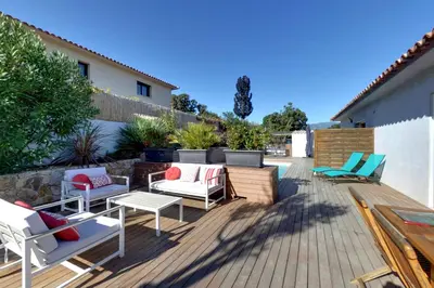 a patio with chairs and tables on a wooden deck at Villa Orethaga appart Ghjallu in Porto-Vecchio