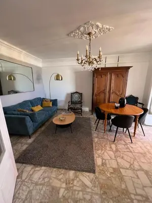 a living room with a blue couch and a table at Appartement climatisé F3 proche plage port et aéroport in Ajaccio