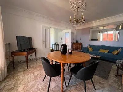 a living room with a table and a blue couch at Appartement climatisé F3 proche plage port et aéroport in Ajaccio