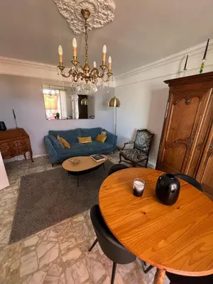 a living room with a table and a blue couch at Appartement climatisé F3 proche plage port et aéroport in Ajaccio
