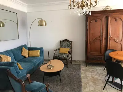 a living room with a blue couch and a table at Appartement climatisé F3 proche plage port et aéroport in Ajaccio