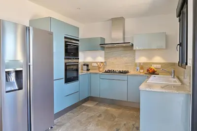a kitchen with blue cabinets and a refrigerator at Résidence Capicciolo Villa A CIGALA in Olmeto