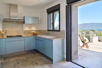 a kitchen with blue cabinets and a view of the ocean at Résidence Capicciolo Villa A CIGALA in Olmeto