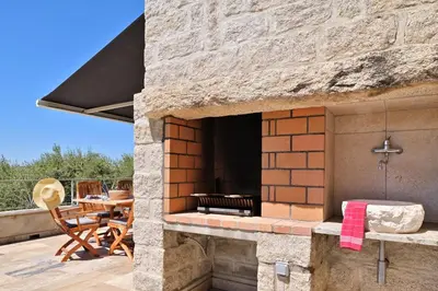 an outdoor oven with a table and chairs on a patio at Résidence Capicciolo Villa A CIGALA in Olmeto