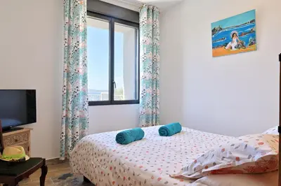 a bedroom with a bed with blue pillows and a window at Résidence Capicciolo Villa A CIGALA in Olmeto