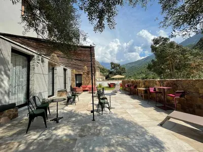 a patio with chairs and tables and a stone wall at CASA VOLTEGIRA in Manso