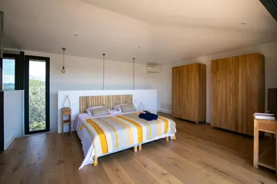 a bedroom with a bed in a room with wooden floors at Villa de luxe surplombant la mer, piscine suspendue in Pianottoli-Caldarello