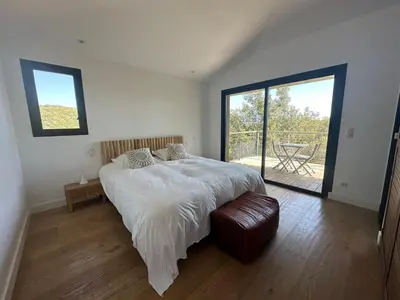 a bedroom with a large bed and a balcony at Villa de luxe surplombant la mer, piscine suspendue in Pianottoli-Caldarello