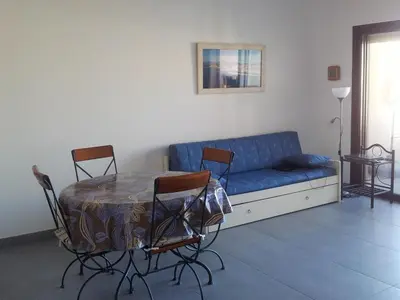 a living room with a blue couch and a table and chairs at Jardins de Quatrina in Propriano