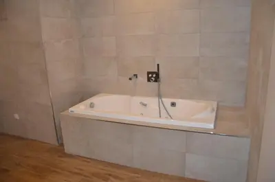 a bath tub in a bathroom with a tile wall at casa funtana d u frusteru in Propriano