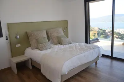 a bedroom with a white bed with a large window at casa funtana d u frusteru in Propriano