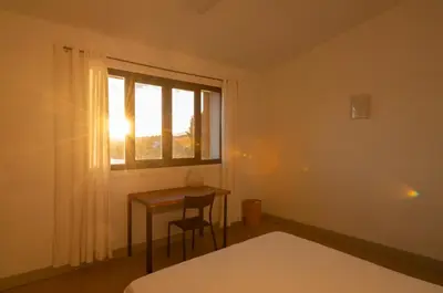 a bedroom with a bed and a desk and a window at Les Salins in Porto-Vecchio