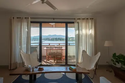 a living room with a table and chairs and a balcony at Les Salins in Porto-Vecchio