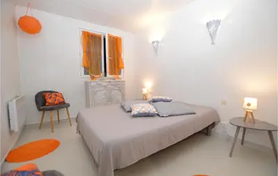 a bedroom with a bed and two tables and a window at 1 Bedroom Lovely Apartment In Propriano in Propriano