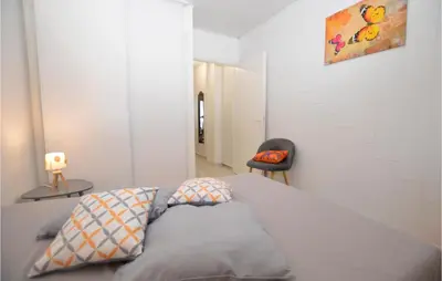 a white room with a bed and a chair at 1 Bedroom Lovely Apartment In Propriano in Propriano