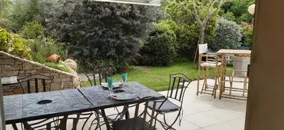 a patio with a table and chairs in a yard at studio 5min plage agosta in Albitreccia