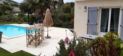 a patio with a table and an umbrella next to a pool at studio 5min plage agosta in Albitreccia
